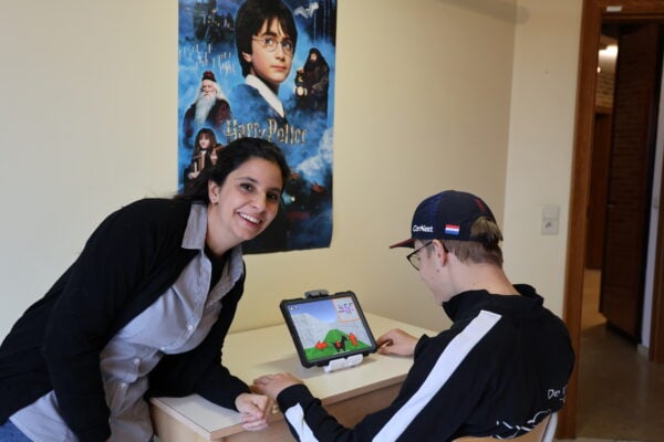 A young adult plays rehabilitative computerised games together with a clinical researcher